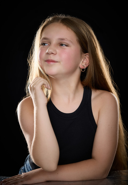 Olivia smiling over her shoulder in a studio headshot on a black backdrop