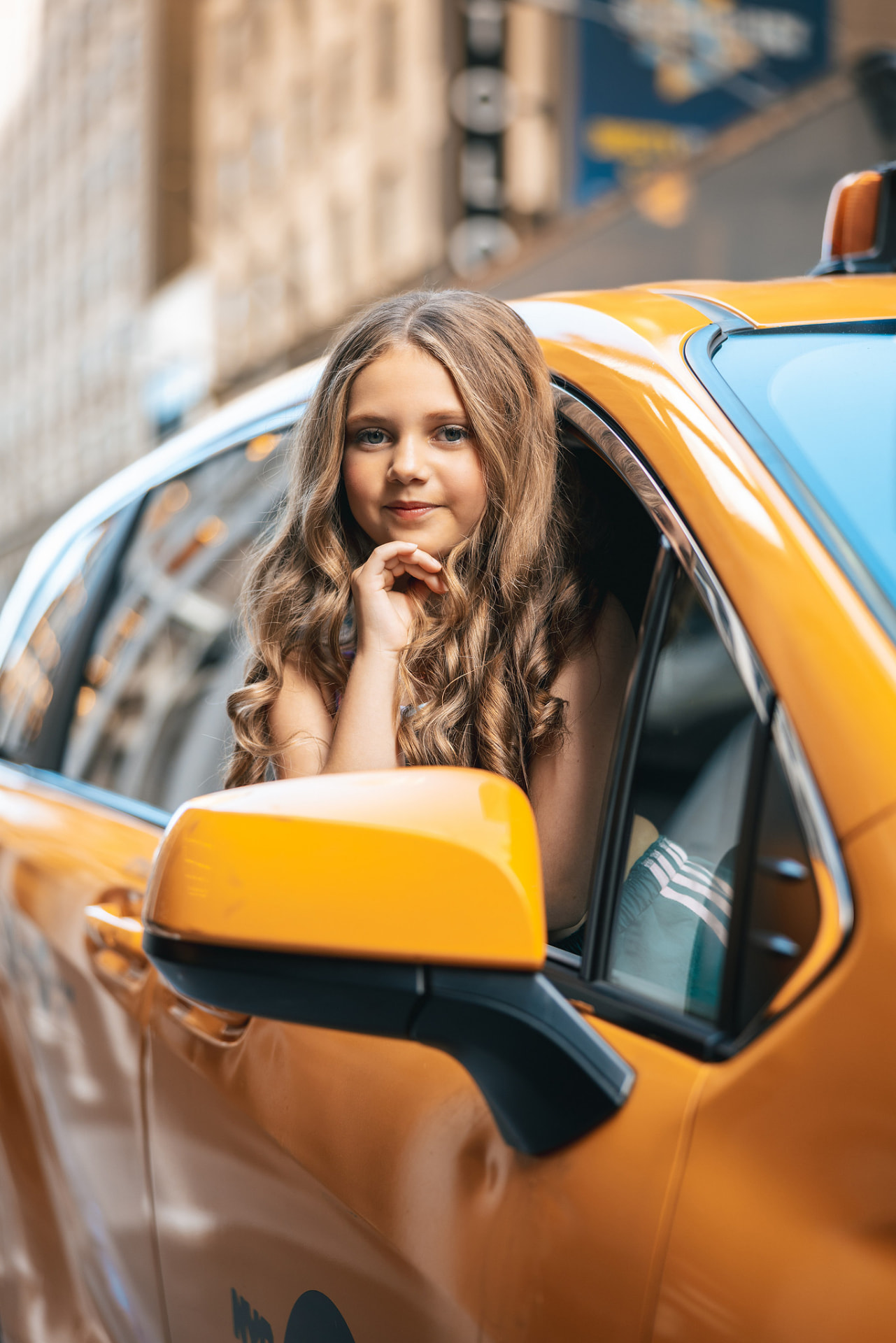 Olivia leaning out of a yellow New York taxi window, chin resting on her hand