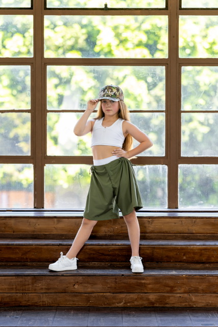 Olivia standing confidently on wooden steps before sunlit windows
