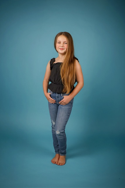 Full-length portrait of Olivia barefoot against a teal studio backdrop