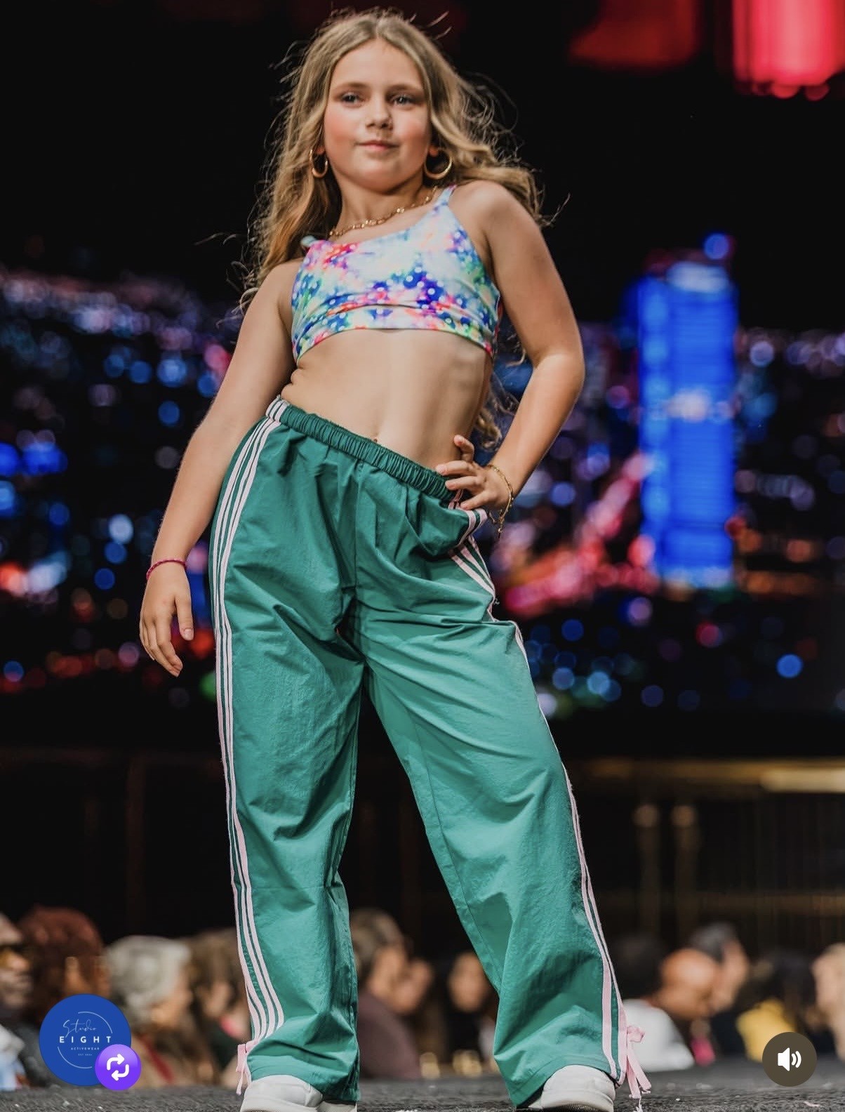 Olivia modeling on a runway in green track pants and a colorful top