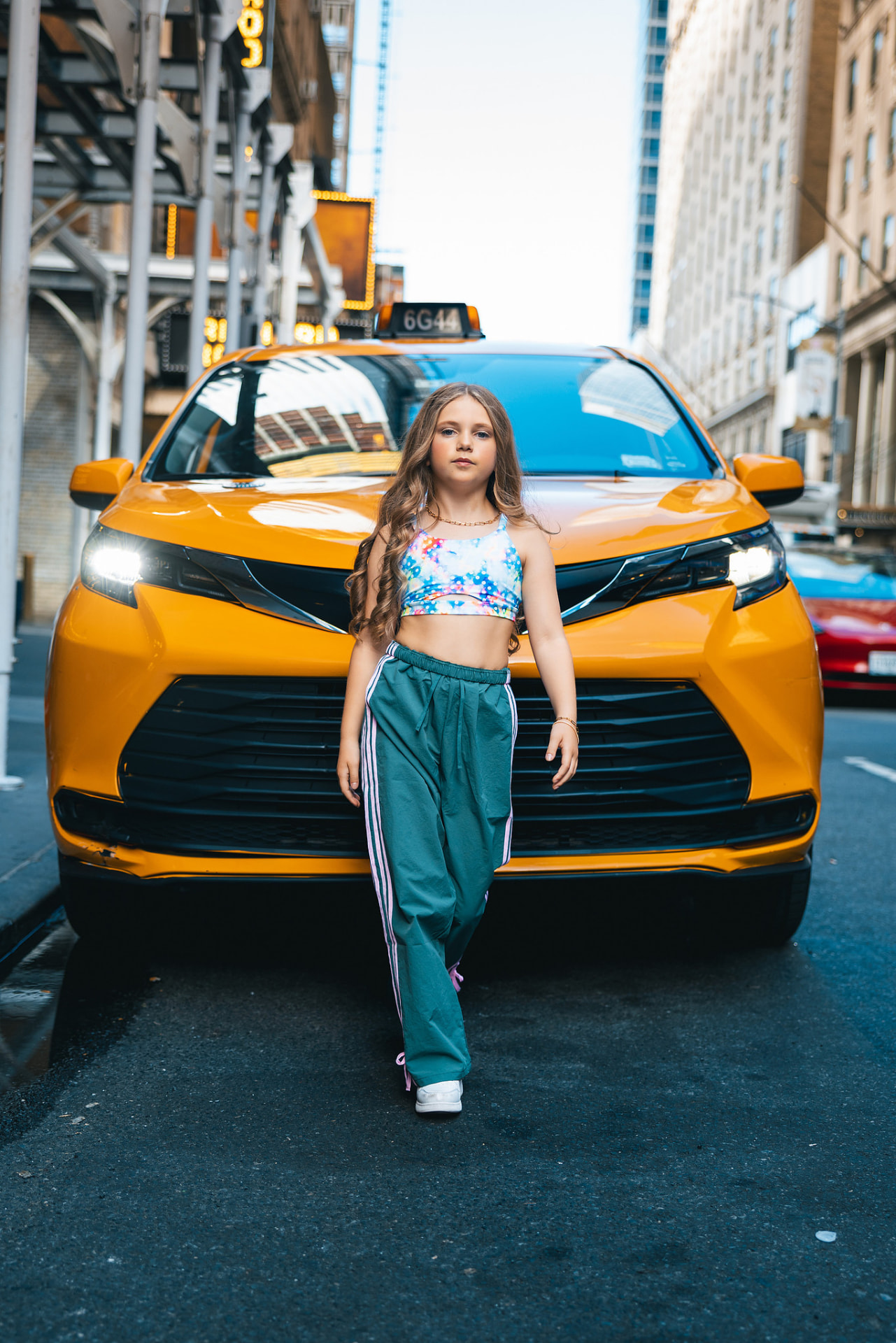 Olivia walking toward the camera in front of a yellow taxi on a Manhattan street
