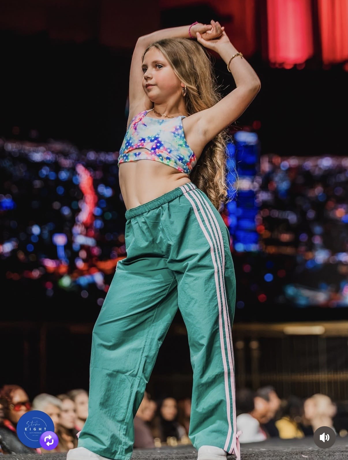 Olivia posing with raised arms on a fashion runway